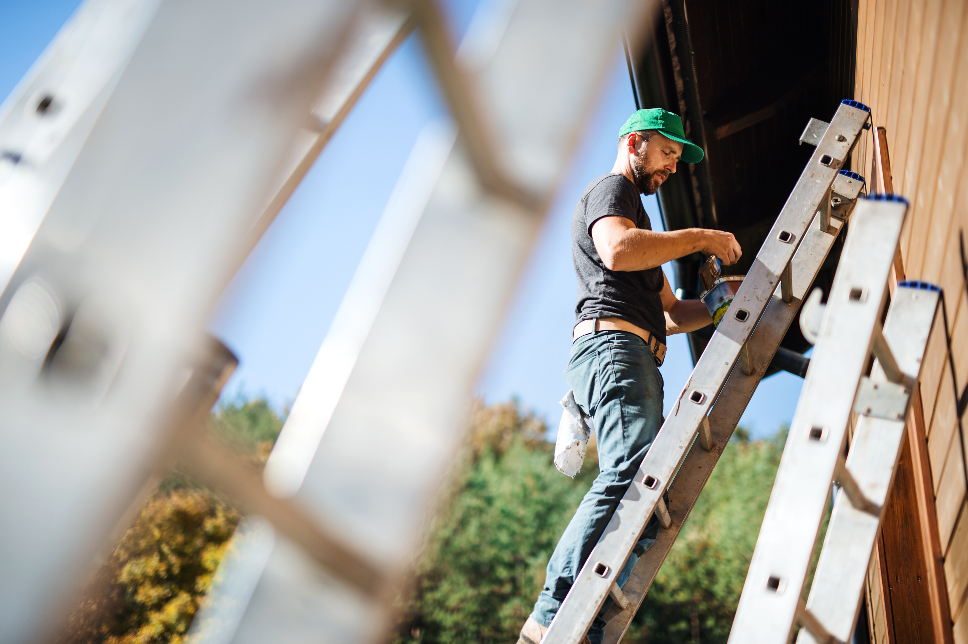 A person painting Hardie Board siding