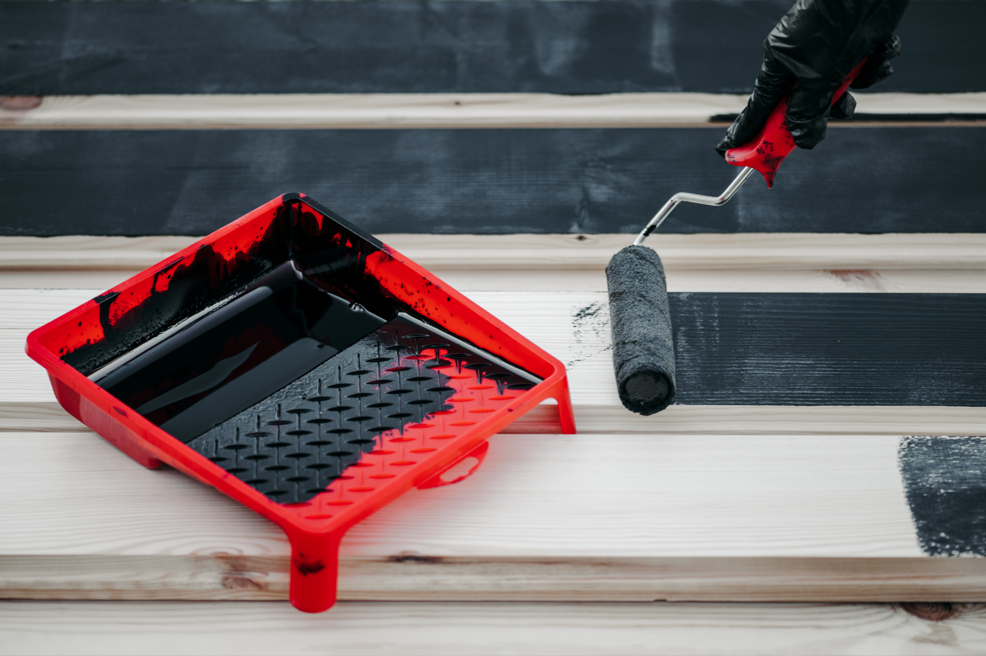 A person painting Hardie Board siding with a roller