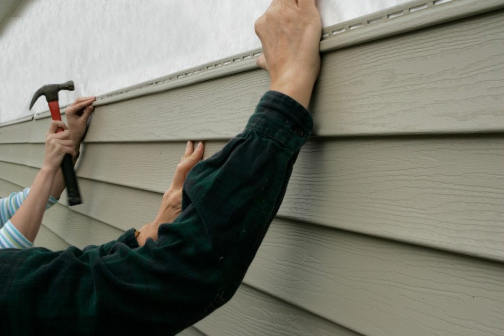 siding installation on the house with sider hands holding siding planks