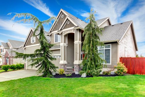 new siding installed by siding contractors in seattle, green grass and trees in front of house and blue sky