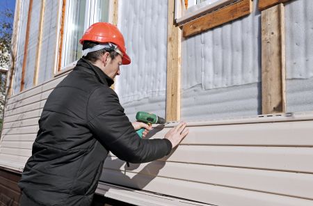 siding installer works on siding installation on a wall