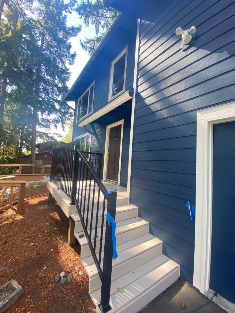 new siding installed on house exterior, white stairs and arctic white trim around garage and windows