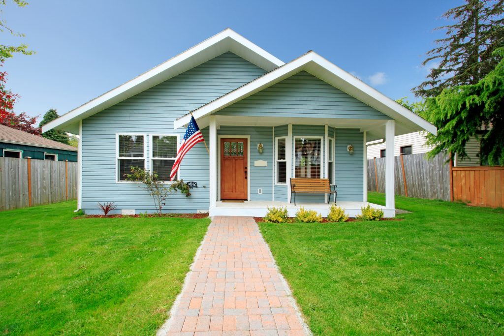 Small clapboard siding house. View of porch with bench and walkway