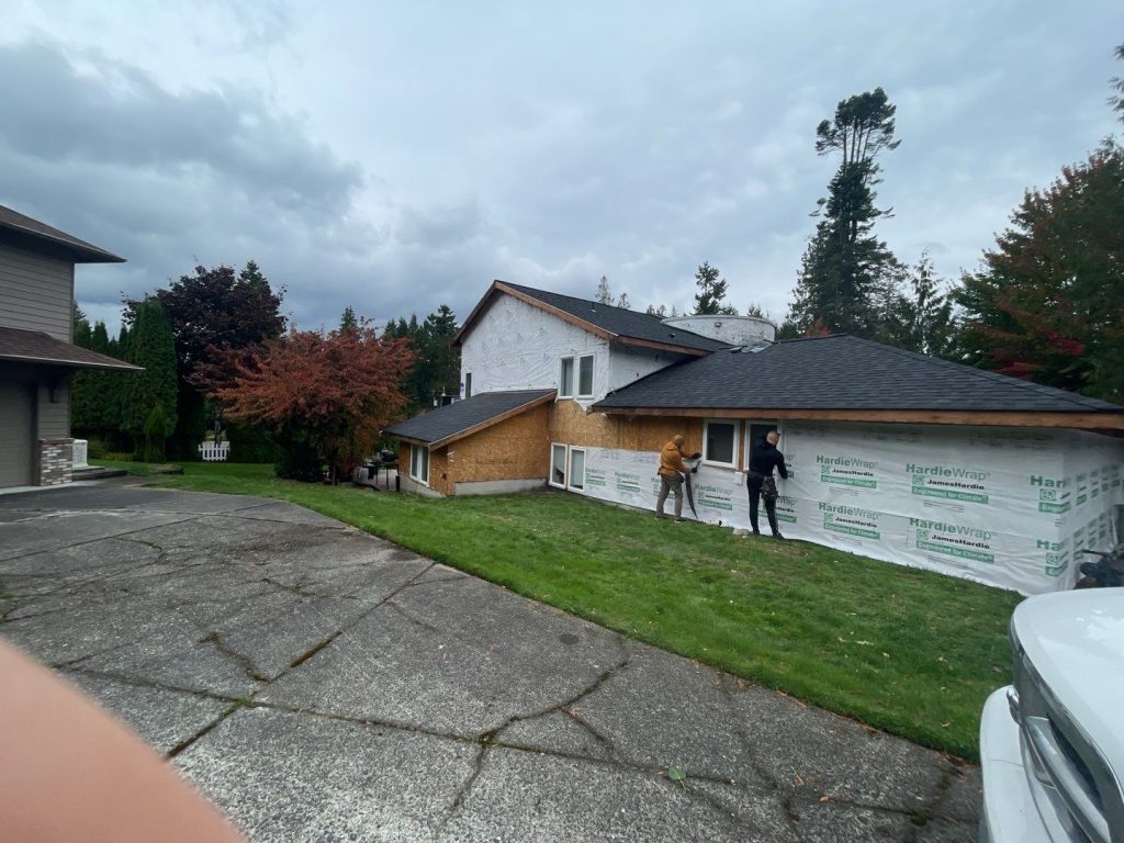 A person installing house wrap on a wall Bellingham Strawbery Avenue