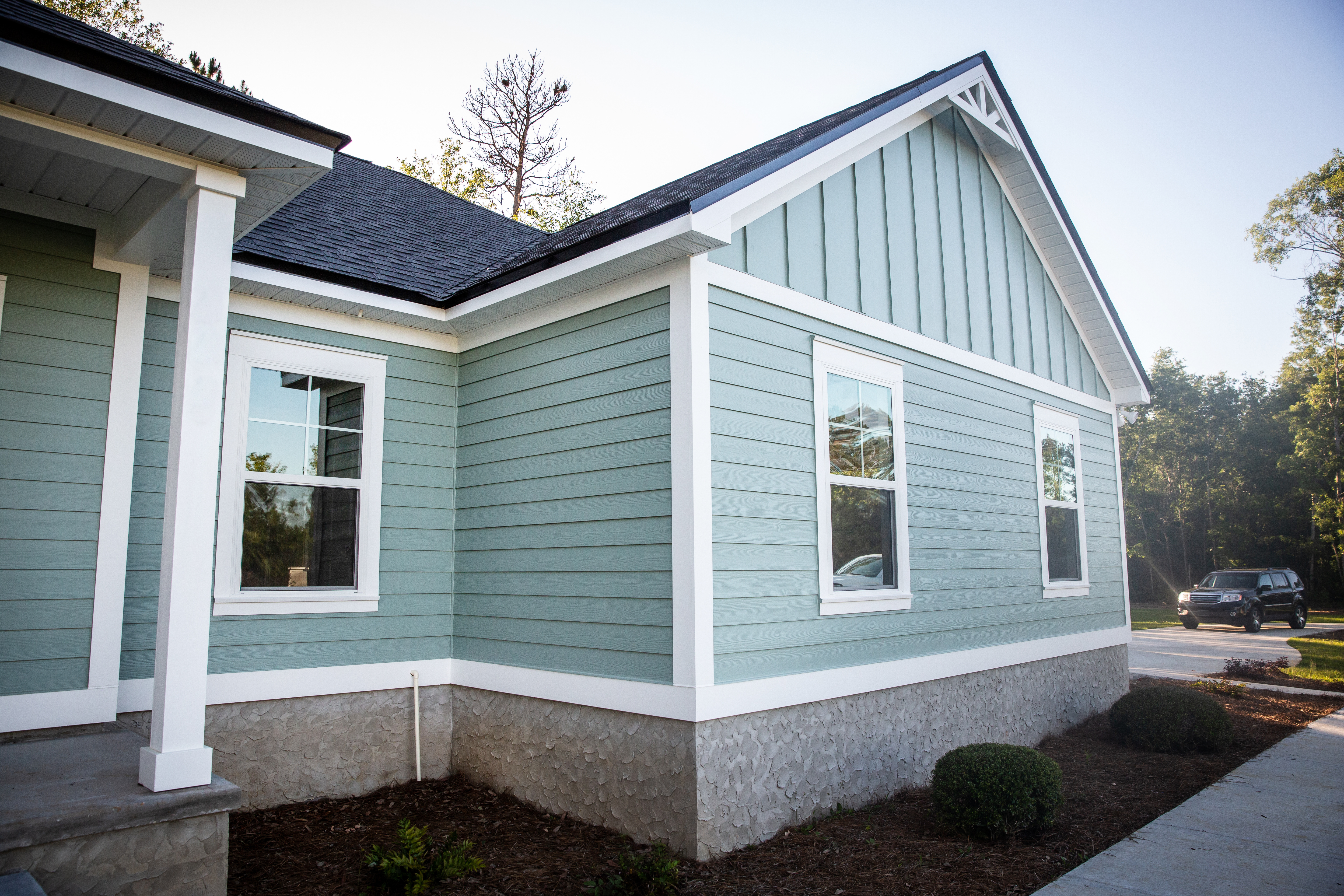 Front view of a brand new construction house with blue siding, a ranch style home with a yard